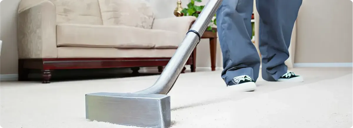 Carpet cleaning technician using a hot-water extraction wand on a light-colored carpet in a living room, Nashville, TN.