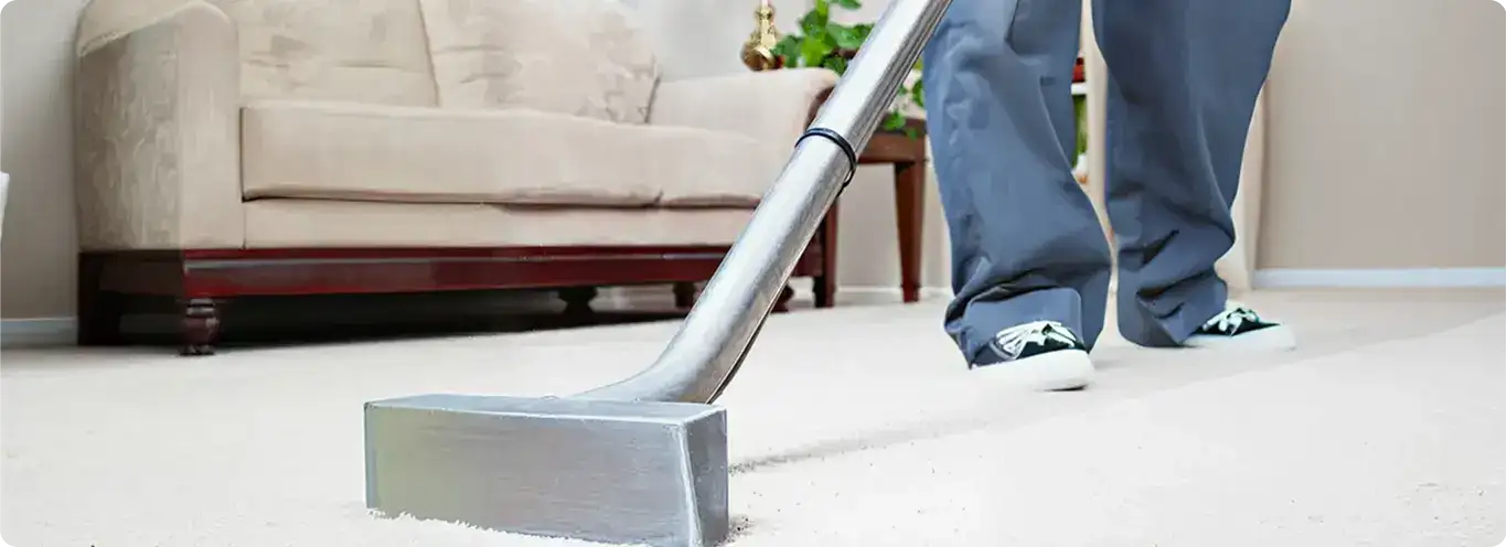 Carpet cleaning technician using a hot-water extraction wand on a light-colored carpet in a living room, Nashville, TN.